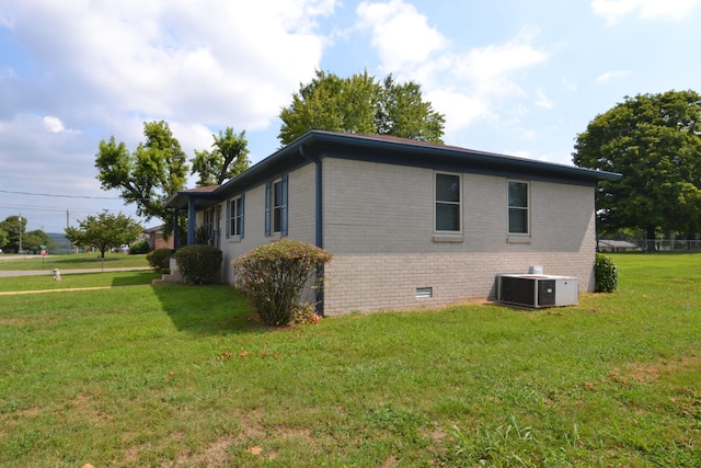 view of side of home with brick siding, crawl space, a lawn, and central AC