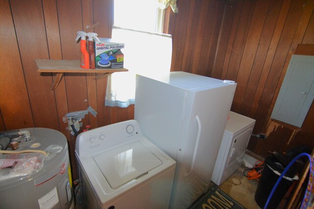 clothes washing area featuring wooden walls, washing machine and dryer, laundry area, and water heater