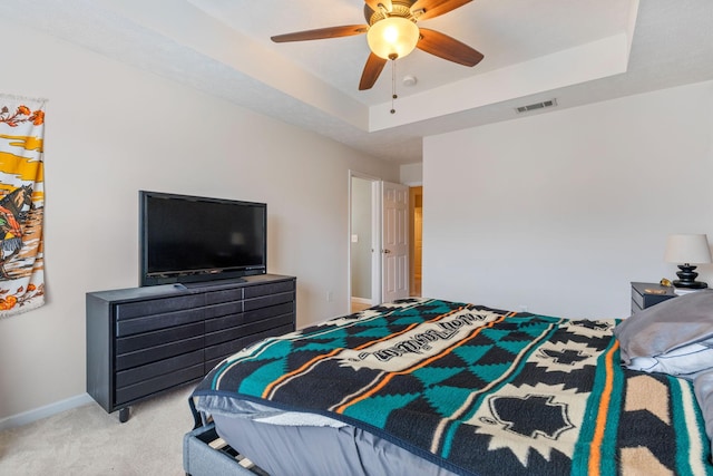 bedroom featuring a ceiling fan, visible vents, baseboards, a raised ceiling, and light colored carpet