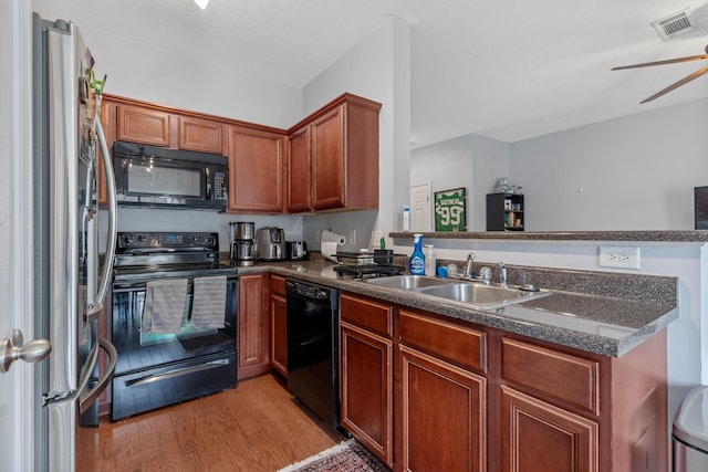 kitchen featuring visible vents, black appliances, a sink, light wood-style floors, and a peninsula