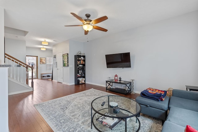 living area with ceiling fan, stairway, baseboards, and hardwood / wood-style floors