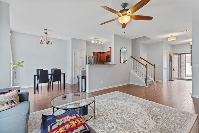 living area featuring visible vents, ceiling fan with notable chandelier, stairway, baseboards, and dark wood-style flooring