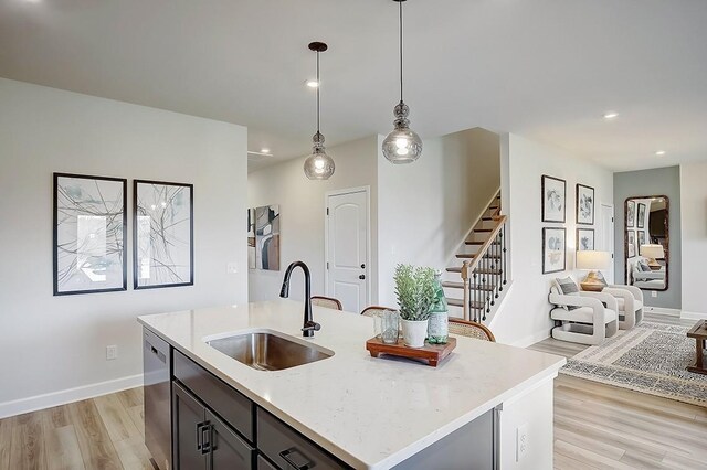 kitchen with light wood-type flooring, pendant lighting, a sink, open floor plan, and dishwasher