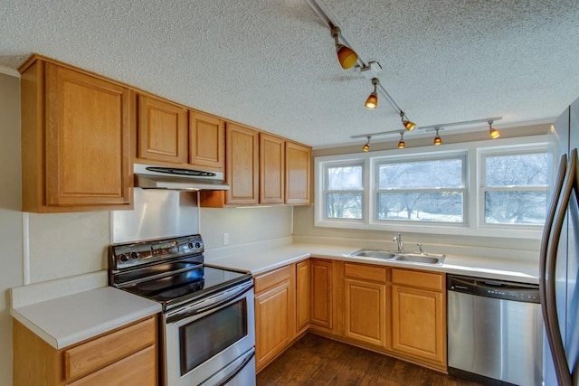 kitchen with under cabinet range hood, light countertops, dark wood-style floors, stainless steel appliances, and a sink