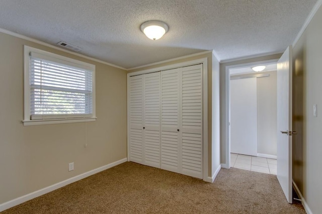 unfurnished bedroom featuring visible vents, carpet, ornamental molding, a closet, and a textured ceiling