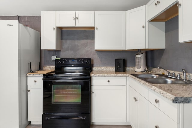 kitchen featuring a sink, white cabinetry, black range with electric stovetop, and light countertops