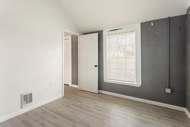 spare room featuring vaulted ceiling, wood finished floors, visible vents, and baseboards