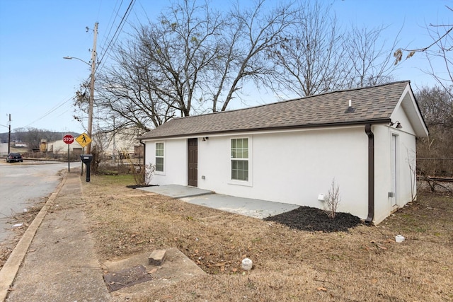 view of front of property featuring a patio area, stucco siding, and a shingled roof