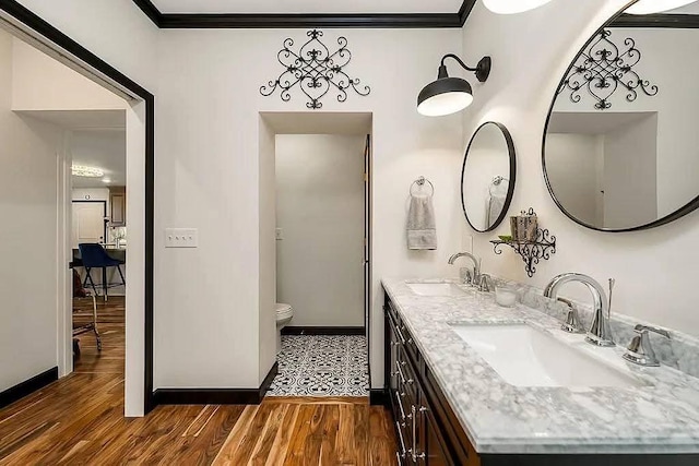 full bath with a sink, toilet, wood finished floors, and ornamental molding