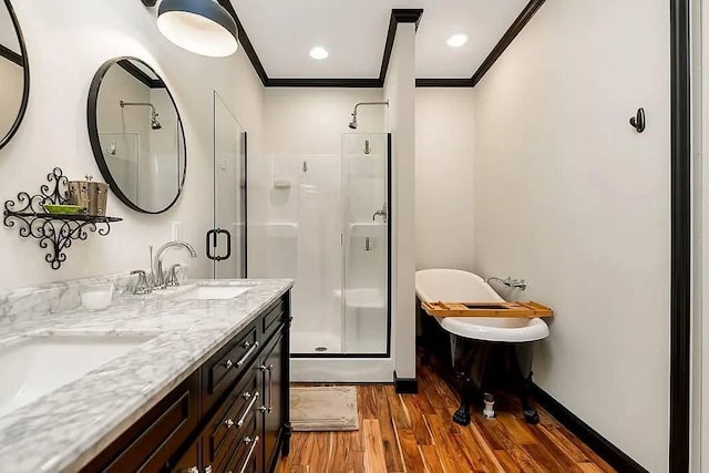 bathroom with crown molding, baseboards, a stall shower, wood finished floors, and a sink