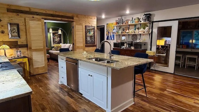 kitchen with a sink, light stone countertops, a center island with sink, white cabinetry, and dark wood-style flooring