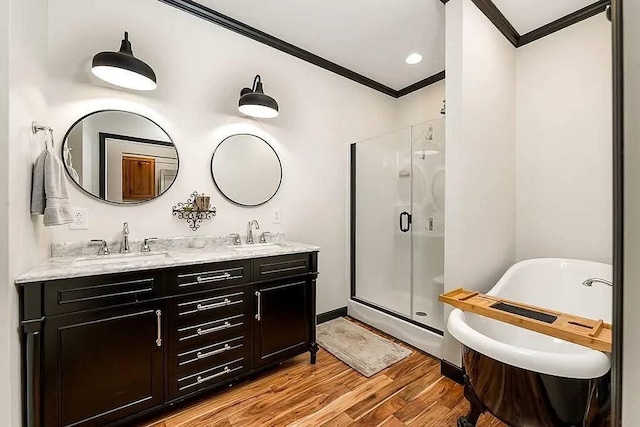 full bath with a sink, a shower stall, wood finished floors, and ornamental molding