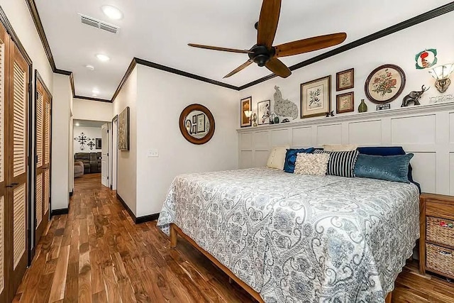 bedroom with visible vents, a ceiling fan, wood finished floors, crown molding, and baseboards