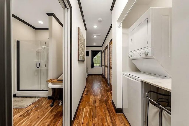 corridor with recessed lighting, stacked washer and clothes dryer, dark wood-style flooring, and crown molding