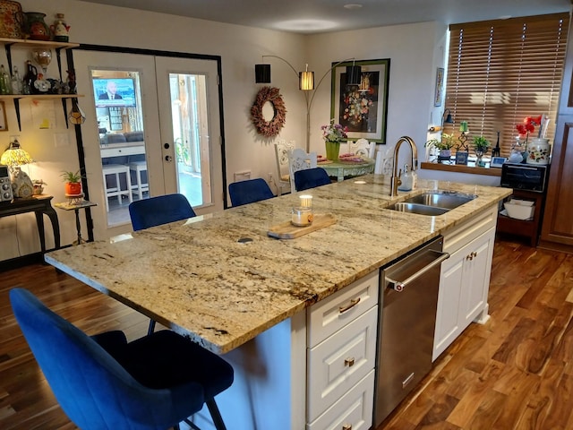 kitchen with dark wood finished floors, light stone counters, stainless steel dishwasher, white cabinetry, and a sink