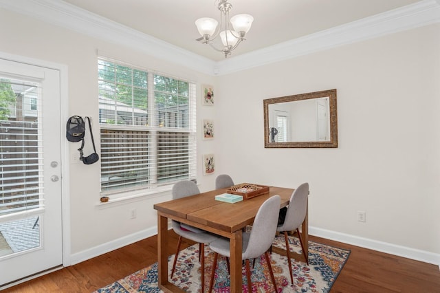 dining area with a healthy amount of sunlight, crown molding, an inviting chandelier, and wood finished floors