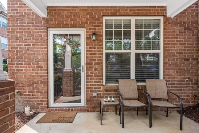 entrance to property with brick siding and a patio area