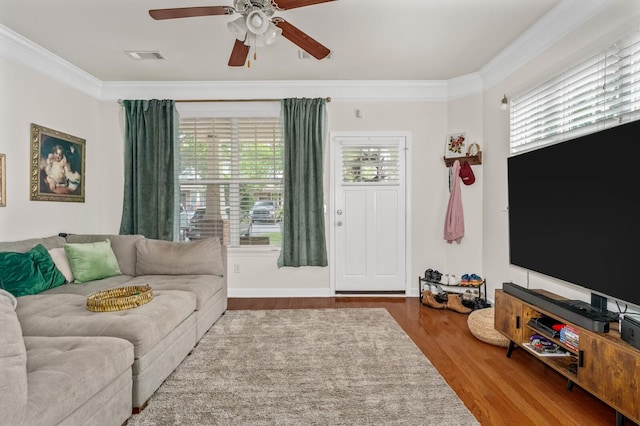 living room with a ceiling fan, crown molding, wood finished floors, and visible vents