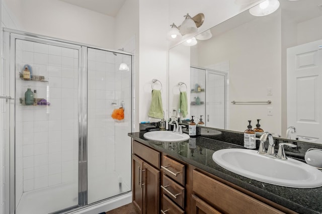 bathroom with double vanity, a stall shower, and a sink