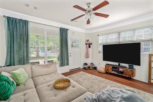 living area featuring visible vents, wood finished floors, and crown molding