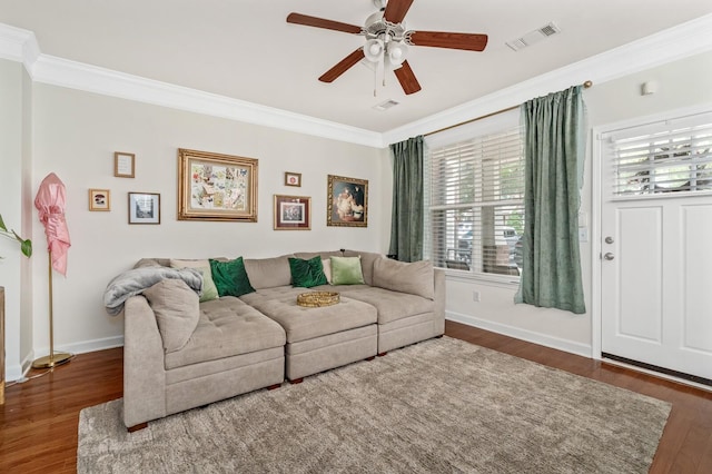 living area with visible vents, wood finished floors, baseboards, and ornamental molding