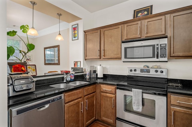 kitchen featuring a sink, decorative light fixtures, brown cabinetry, and stainless steel appliances