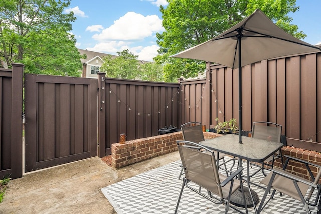 view of patio with outdoor dining area, fence, and a gate