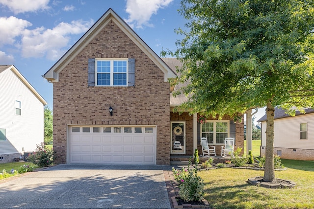 traditional home with a front lawn, a porch, concrete driveway, an attached garage, and brick siding