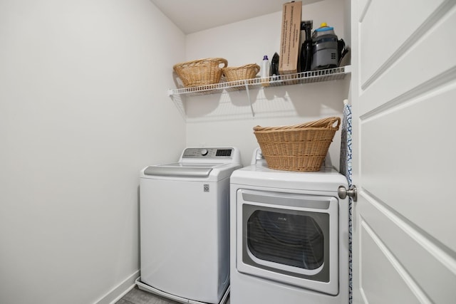 washroom featuring baseboards, separate washer and dryer, and laundry area