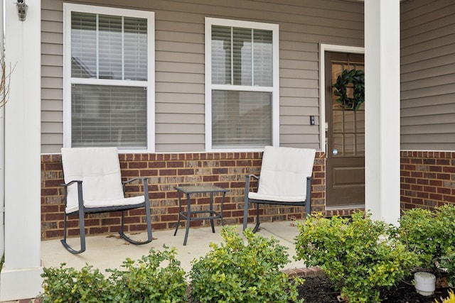 doorway to property with brick siding and covered porch