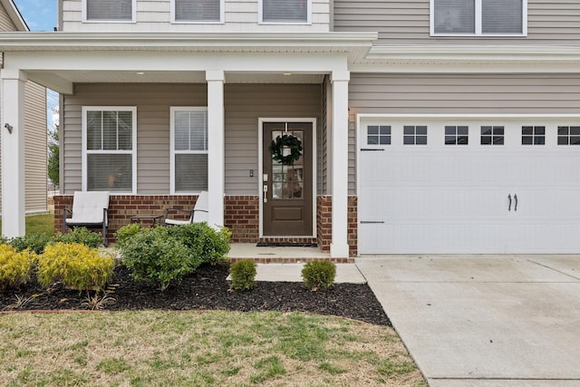 doorway to property with a garage, brick siding, covered porch, and concrete driveway