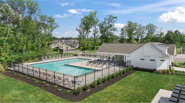 community pool featuring a patio, a lawn, and fence