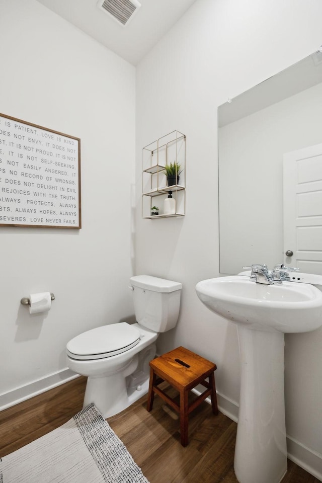 bathroom with wood finished floors, visible vents, baseboards, a sink, and toilet