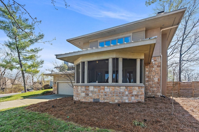 view of side of home featuring fence, a sunroom, a garage, stone siding, and crawl space