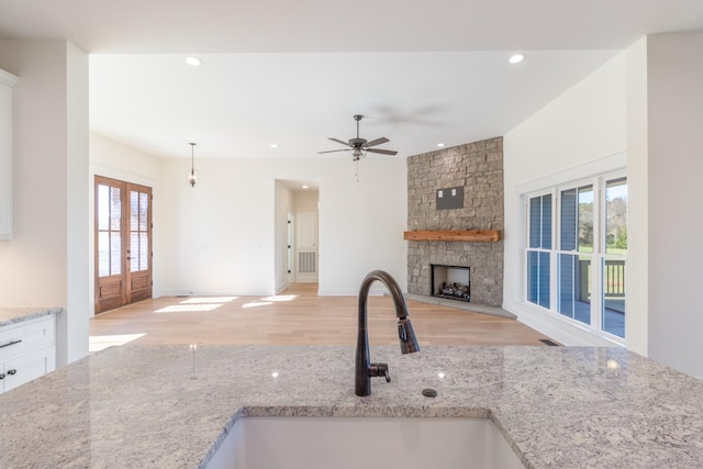 856 Tucker Rd, Dickson, TN 37055 - kitchen featuring light wood-style floors, a stone fireplace, white cabinets, a ceiling fan, and open floor plan