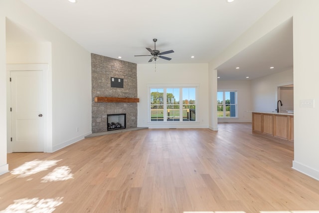 unfurnished living room featuring baseboards, a fireplace, recessed lighting, ceiling fan, and light wood-style floors