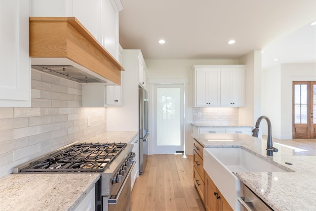 856 Tucker Rd, Dickson, TN 37055 - kitchen featuring premium appliances, custom exhaust hood, light stone countertops, white cabinets, and light wood-type flooring