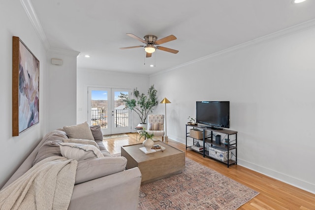 living area featuring a ceiling fan, french doors, light wood-style floors, crown molding, and baseboards