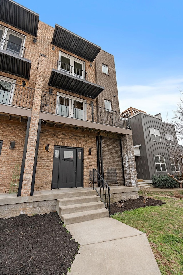 view of front facade featuring a balcony and brick siding