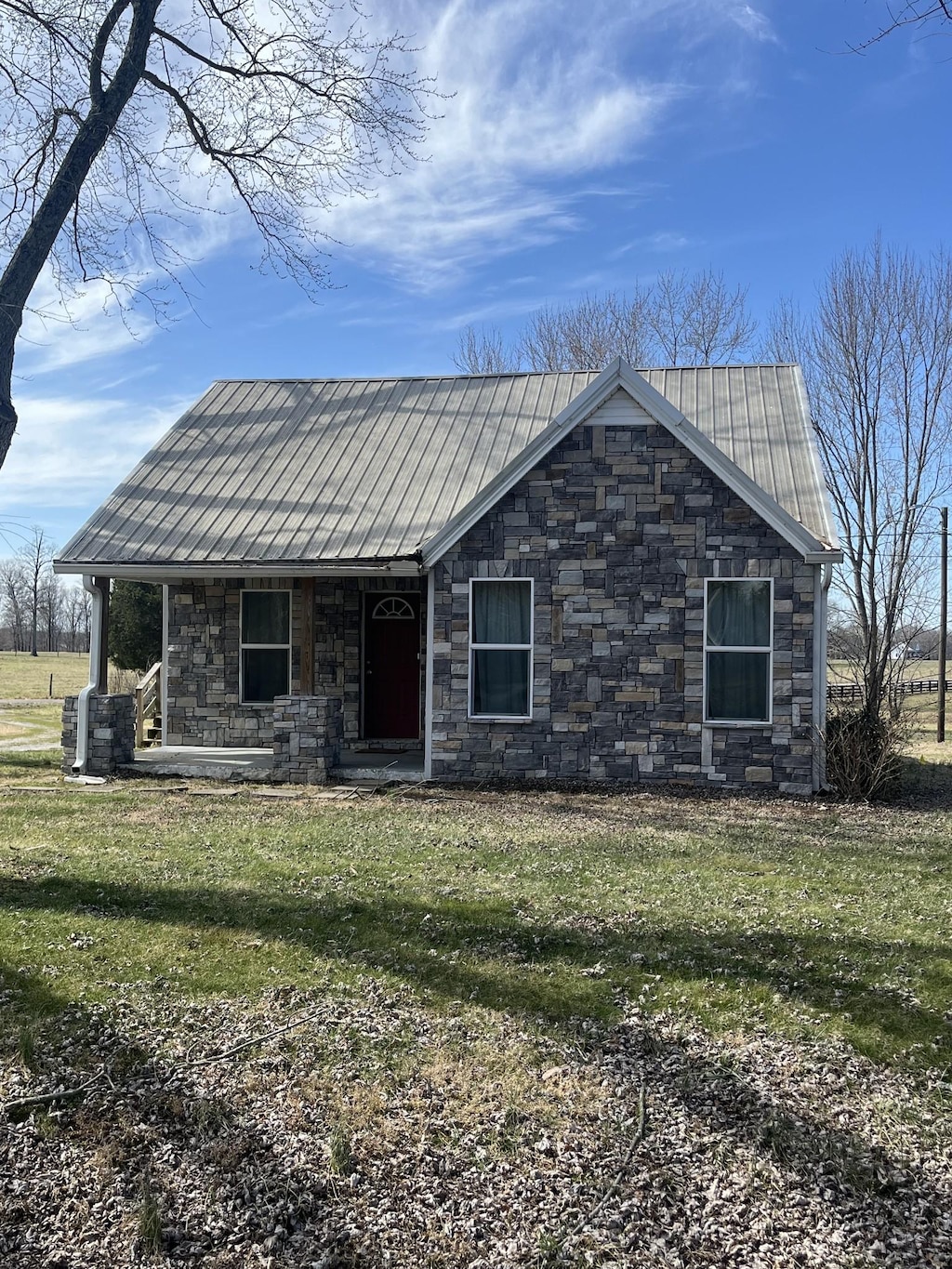 view of front of house with a front lawn, a porch, stone siding, and metal roof