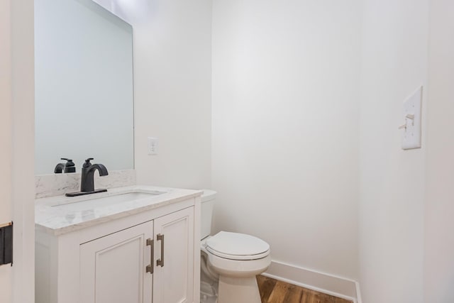 bathroom featuring toilet, vanity, baseboards, and wood finished floors