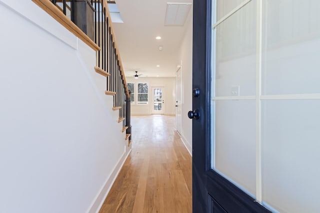 corridor featuring wood finished floors, visible vents, baseboards, recessed lighting, and stairs