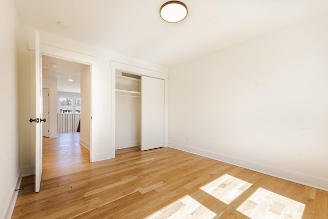 unfurnished bedroom featuring a closet, baseboards, and light wood finished floors