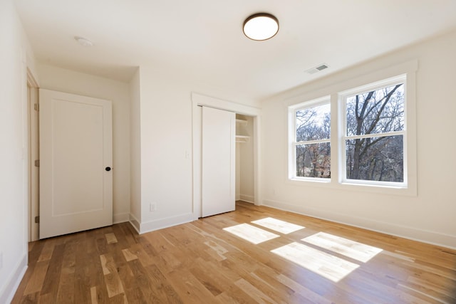 unfurnished bedroom featuring visible vents, baseboards, a closet, and light wood finished floors