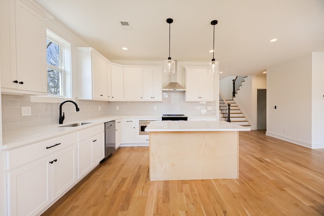 kitchen featuring light wood-type flooring, a sink, a center island, stainless steel appliances, and wall chimney exhaust hood