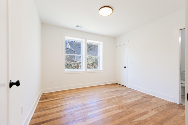 spare room featuring visible vents, baseboards, and light wood finished floors