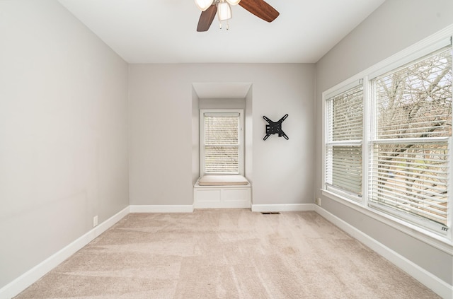 empty room with a ceiling fan, baseboards, and light carpet