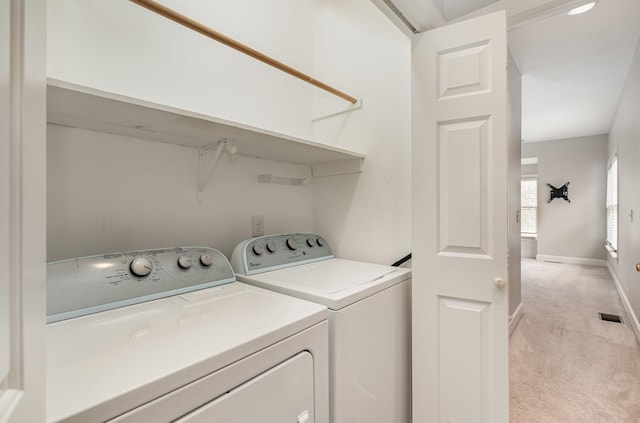 clothes washing area featuring visible vents, washing machine and dryer, baseboards, light colored carpet, and laundry area