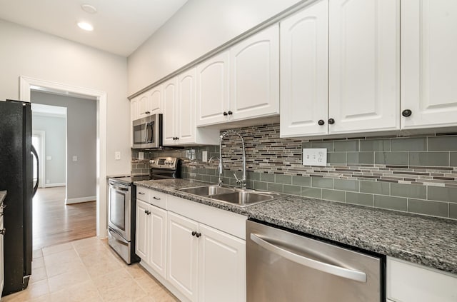 kitchen featuring light tile patterned floors, a sink, white cabinets, appliances with stainless steel finishes, and backsplash