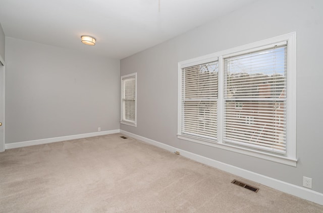 spare room with light colored carpet, visible vents, and baseboards